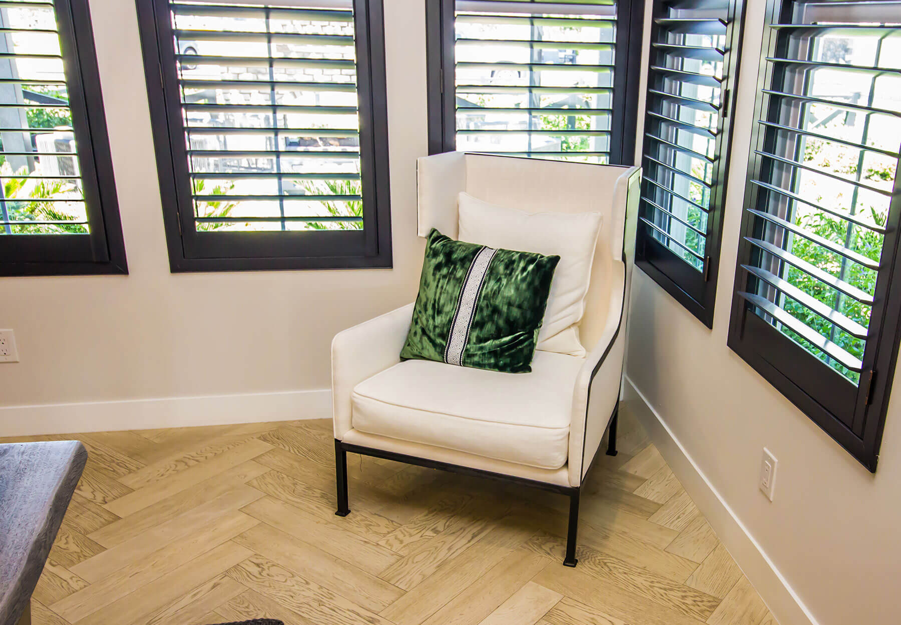 A room with a chair and wood shuttered windows